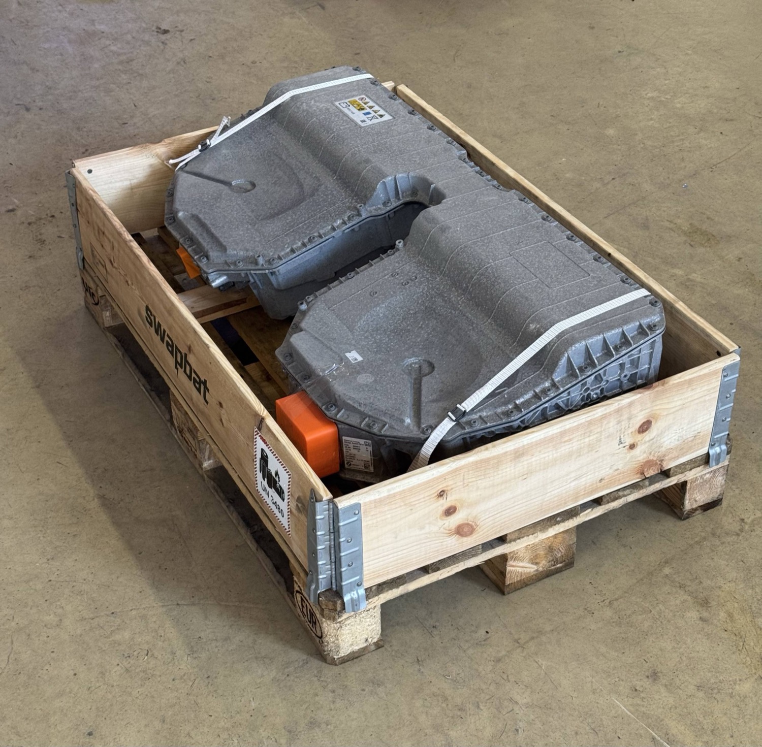Remanufactured BMW high-voltage battery packs strapped in a Swapbat shipping crate, ready for delivery