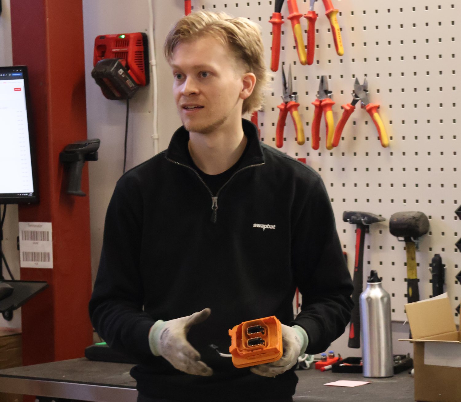 Swapbat technician holding a high-voltage connector at the repair bench