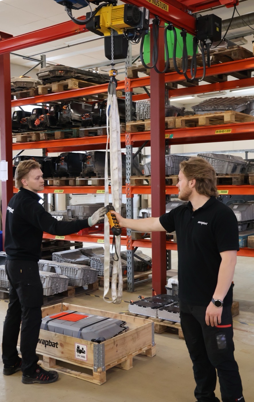 Swapbat technicians lifting a high-voltage battery pack with the overhead crane